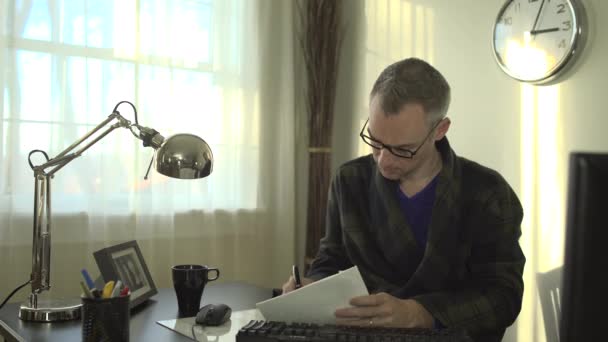 A man works at a clean desk with a computer and keyboard — Stock Video