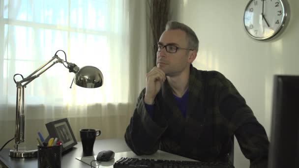 Un hombre trabaja en un escritorio limpio con una computadora y un teclado — Vídeo de stock