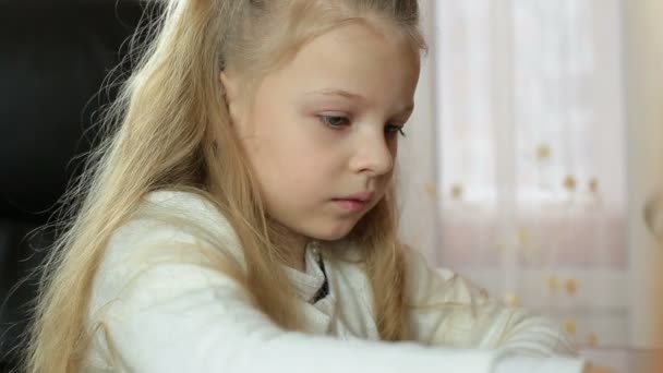 Маленька красива дівчинка малює з кольоровими маркерами за столом в кімнаті — стокове відео