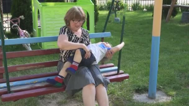 Abuela y nieto sentado en el patio de recreo — Vídeo de stock