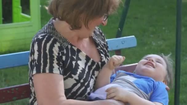Бабушка и ее внук играют на детской площадке — стоковое видео