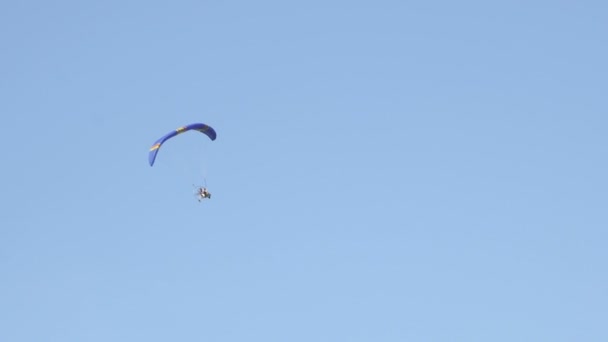 Parachute met motor vliegen op blauwe bewolkte hemel — Stockvideo