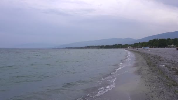 Grusstrand med alger. Vackra bergen i bakgrunden — Stockvideo