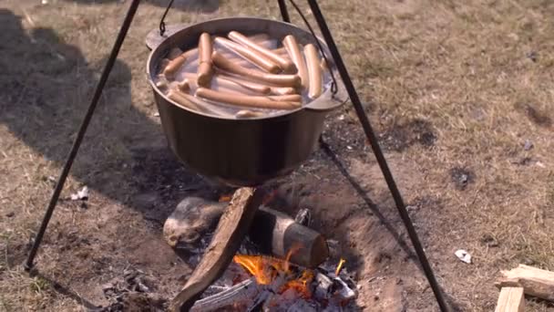 Vaření klobás v litinový kotel — Stock video
