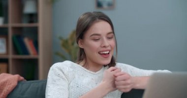 Dizüstü bilgisayar kullanırken görüntülü konuşma yapan genç bir kadın. Güzel bir bayan, evdeki kanepede otururken işaret diliyle gülümseyip seni sevdiğimi söylüyor. İşitme kaybı kavramı.