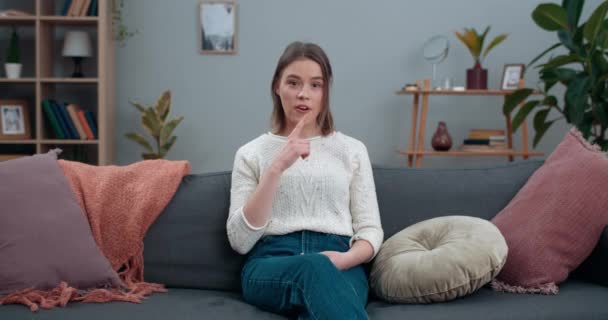 Millennial žena ukazuje s hluchoněmým znakovým jazykem jsem hluchý. Žena se ztrátou sluchu dívá do kamery a říká nonverbální frázi, zatímco sedí na pohovce doma. — Stock video