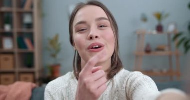 Kadının video görüşmesi yaptığı ve akıllı telefonun ön kamerasını kullandığı yakın çekim görüntüsü. Kadın güzel insan gülümsüyor ve işaret diliyle 