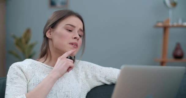 Millennial vrouwelijke persoon die video gesprek tijdens het gebruik van laptop. Mooie vrouw lachend en vertellend met gebarentaal mis ik je terwijl je thuis op de bank zit. Gehoorverlies. — Stockvideo