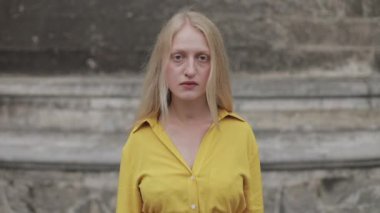 Mutsuz bir kadının başını kaldırıp kameraya bakması. Şehir caddesinde duran melankolik ve hüzünlü kadın portresi. Yakınlaştır.