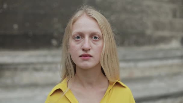 심각 한 여성이 고개를 돌리고 카메라를 찾는 모습을 가까이서 볼 수있다. 파란 눈에 금발 머리에 시가지에 서 있는 슬픈 여자의 모습. 옥외에서. — 비디오