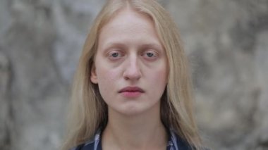 Kameraya bakan mutsuz yalnız kadının yakın görüntüsü. Şehir caddesinde duran mavi gözlü ve sarı saçlı kadın portresi. Depresyon kavramı. Açık havada. Yakınlaştır.