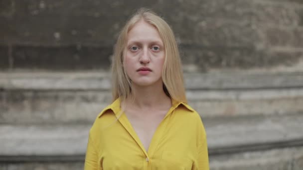 진지 한 여자가 우울하고 슬픈 감정으로 카메라를 쳐다보는 모습. 파란 눈에 금발의 여자가 거리에 서 있는 모습. 줌인. — 비디오