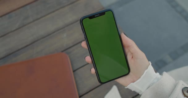 女性の手をモックアップ画面のスマートフォンを保持のクロップビュー。屋外で緑の携帯電話を持つ未知の女性の人。クロマキーの概念. — ストック動画