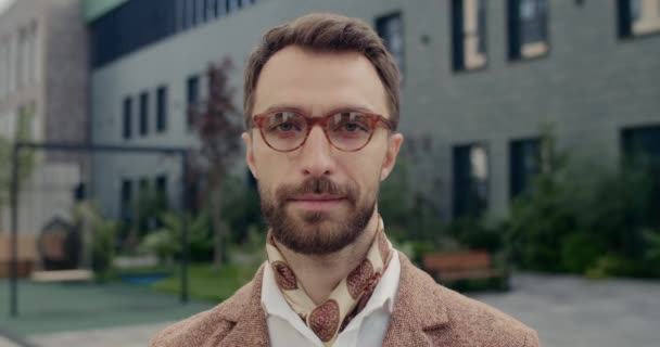 Imagen de un hombre guapo con barba mirando a la cámara. Vista de la cosecha de la persona masculina con estilo con expresión de cara seria mientras está de pie en la calle. Concepto de estilo de vida, éxito. — Vídeo de stock