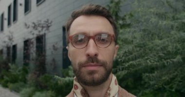 Ciddi sakallı bir adamın portresi. Eşarplı ve kameraya bakıyor. Şehir sokağında duran gözlüklü, kendine güvenen yakışıklı adamın yakın görüntüsü. Vesikalık fotoğraf kavramı.