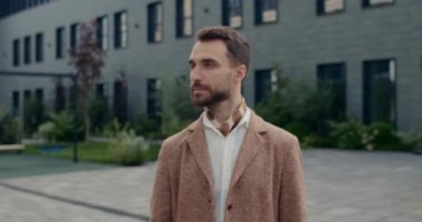 Sakallı ve kameraya poz veren yakışıklı bir adamın portresi. Tarz sahibi bir erkeğin sokakta dikilirken başını çevirmesi. Yakınlaştır. Yaşam tarzı kavramı, başarı.