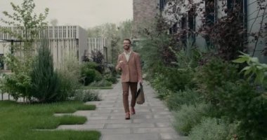 Gözlüklü neşeli sakallı adam ileriye bakıyor ve çantasıyla kahve bardağı taşırken gülümsüyor. Şık bir işadamı sokakta yürürken mutlu bir şekilde atlıyor..