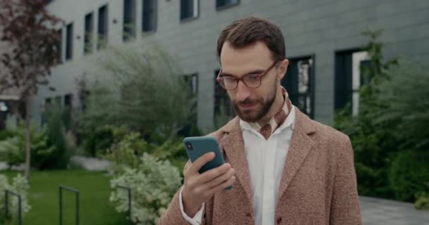 Oříznout pohled na muže v brýlích s dobrou zprávou na jeho smartphonu a radovat se. Stylový vousatý podnikatel s krkem dělat šťastný výraz obličeje a křik při použití telefonu. — Stock video