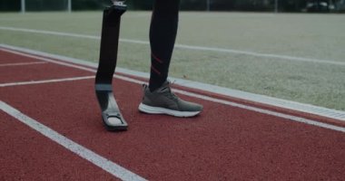 Spor sahasında duran protezli engelli erkek görüntüsü. Bacağı kesilmiş bir erkek sporcu koşmaya hazırlanıyor. Motivasyon sporu görüntüsü kavramı.