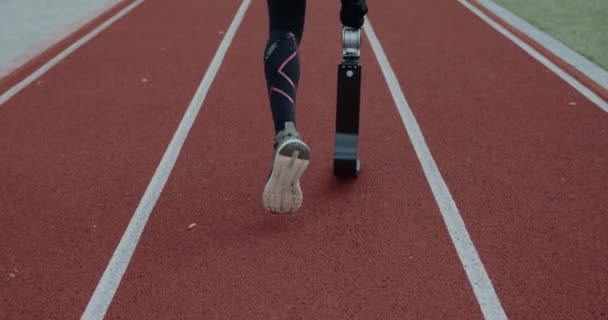 Вид сзади на неизвестного инвалида-мужчину с протезными ходунками на спортивной площадке. Бегун-ампутант готовится. Концепция мотивационных спортивных кадров. — стоковое видео