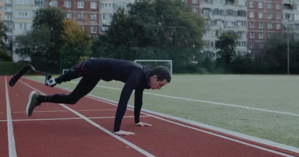 Sterke gehandicapte mannelijke sporter met prothetisch lopende messen die push-ups doen op het sportveld. Man met geamputeerd been die buiten traint. Concept van motiverende sportbeelden. — Stockvideo