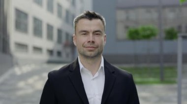 Kameraya bakan olgun CEO 'nun portresi. 40 'lı yaşlarda, ofis binalarının yanında poz veren resmi kıyafetler giyen yakışıklı bir adam. İş ve başarı kavramı.