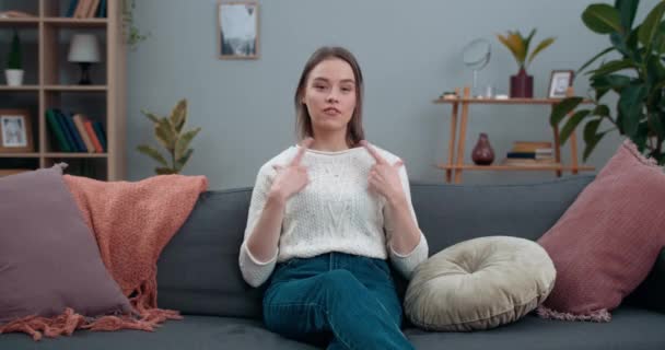 Millennial kvinna säger icke-verbal fras vackert liv när du sitter på soffan hemma. Glad kvinna som tittar till kameran och kommunicerar med dövstumma teckenspråk. — Stockvideo
