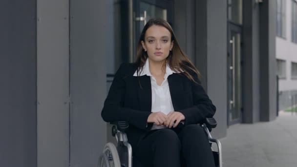 Portrait de jolie femme PDG en costume assis en fauteuil roulant dans la rue de la ville. Crop view of disabled attractive female person looking to camera outdoors. Concept de personnes motivées. — Video