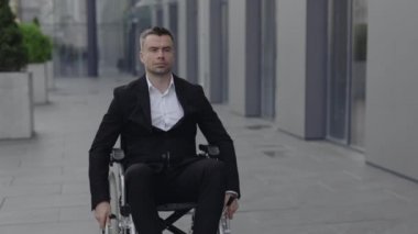 Tekerlekli sandalyedeki işadamının caddeye bakarken önüne baktığı ekin manzarası. Ofis binasının yanındaki tekerlekli sandalyede başarılı bir erkek CEO yöneticisi. Motivasyon kavramı, ızgara.