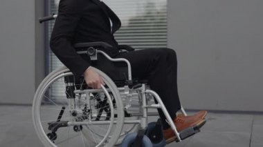 Tekerlekli sandalyedeki işadamının portresi başını çeviriyor ve sokakta dikilirken kameraya bakıyor. Ofis binası yakınlarında ciddi engelli erkek CEO yöneticisi. Motivasyon kavramı, başarı.