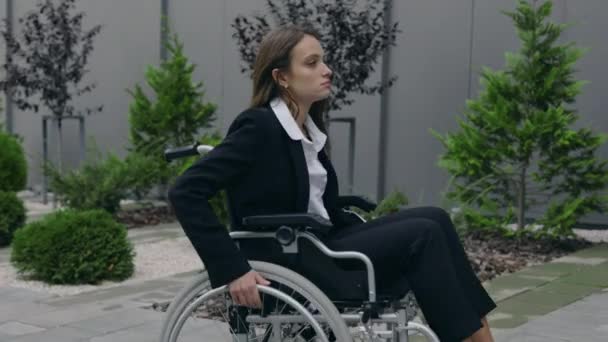 Вид на урожай красивой женщины в костюме, толкающейся на инвалидном кресле на улице. Инвалидная женщина идёт на работу и останавливается возле служебной лестницы. Концепция препятствий, барьеров. — стоковое видео