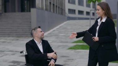 Engelli bir adama belgeli güzel bir kadın geliyor ve dışarıda elini sıkıyor. Mutlu erkek ve kadın işçiler birbirlerini selamlıyor, gülümsüyor ve konuşuyorlar..