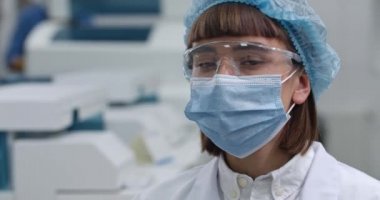 Koruyucu maskeli kadın portresi ve Google 'da kafasını çevirip kameraya bakan kadın. Laboratuvarda beyaz önlüklü ve kabarık şapkalı bir kadının portresi. Tıp kavramı.