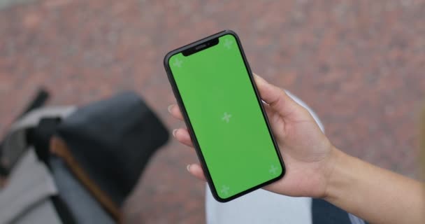 Lviv, Ukraine - August 06, 2019: Top view of phone in woman hand while sitting at street. Female person holding smartphone with green template screen. Concept of chroma key, mock up. — Stock Video
