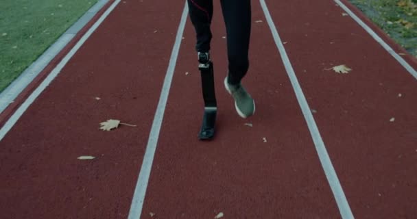Deportista masculino discapacitado con pierna amputada con hoja protésica trotando en el campo de deportes. Atleta masculino discapacitado en pista al aire libre. Concepto de salud, deporte, red. — Vídeo de stock