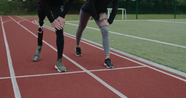 Engelli erkek ve kadın sporcuların yerlerini almaları ve koşmaya başlamaları. Koşu bıçağıyla koşan erkek sporcu ve stadyumda yarış pistinde koşan kadın.. — Stok video