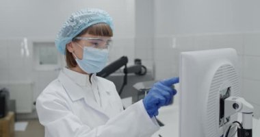 Koruyucu maskeli kadın çalışanın ekin görüntüsü ve google 'da verileri bilgisayara girmesi. Laboratuvarda yazarken cam ilaç şişesi tutan soyguncu ve kabarık kepli bilim adamı..