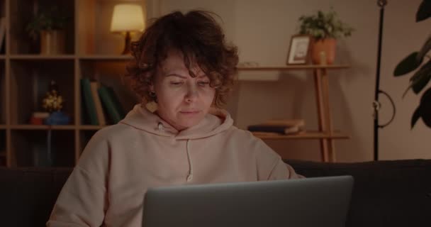 Crop view of beautiful woman using laptop while sitting on sofa at home. Female person with short wave hair browsing internet and looking at computer screen.Concept of free time. — Stock Video