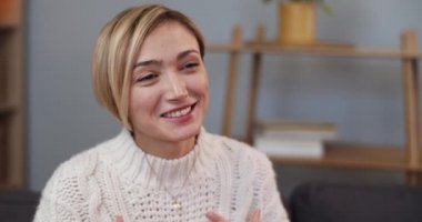 Kısa sarı saçlı, konuşan ve gülümseyen pozitif kadının yakın görüntüsü. Çekici bir kadın kanepede otururken iletişim kuruyor. İçeride. İnsanların duyguları kavramı.