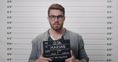 Karakolda fotoğraf çekilirken sakallı ve bıyıklı sert adamın portresi. Gözlüklü, poz veren ve kameraya bakan bir erkek. Sabıka fotoğrafı kavramı.