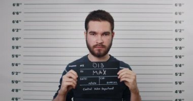 Bıyıklı ve sakallı bir gencin portresi. Polis merkezinde fotoğraf için tabela tutuyor. Milenyum insanının poz verdiği, kafasını kaldırdığı ve kameraya baktığı ekin manzarası..