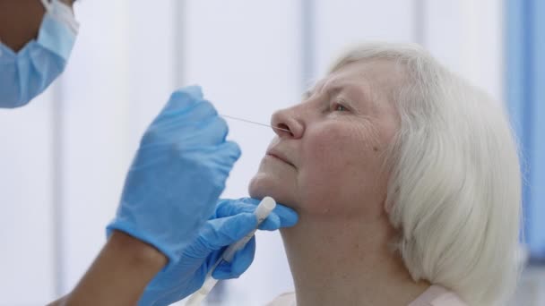 Vista delle colture dell'operaio medico in maschera protettiva che preleva un campione di PCR dal naso della paziente in pensione in camera d'ospedale. Concetto di diagnostica Covid. — Video Stock