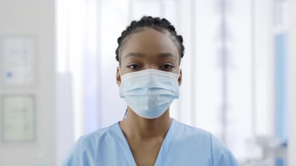 Close up view of afro - american woman in medical protective mask looking to camera. Portrait of female medical worker with dreadlocks posing in hospital . Concept of health care. — Stock Video