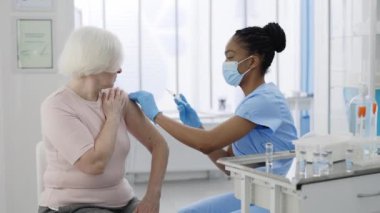 Senior women processing vaccination procedure in private clinic hospital. Professional doctor doing vaccine injection against coronavirus. Concept of health care, vaccination program