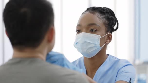 近距离观察非洲裔美国女护士戴着防护面罩和手套，从医院里的男人喉咙里取出抹布的情景。PCR诊断方法的概念，快速围产期检测。Covid-19. — 图库视频影像