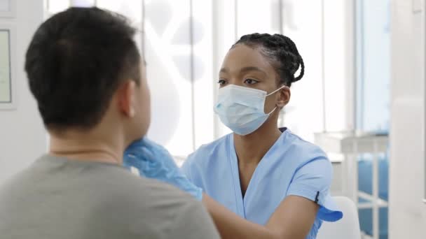 Schnittansicht einer Krankenschwester in Schutzmaske und Handschuhen, die dem Mann im Krankenhaus einen Abstrich von der Nase abnimmt. Konzept der PCR-Diagnosemethode, Covid-Schnelltest. — Stockvideo