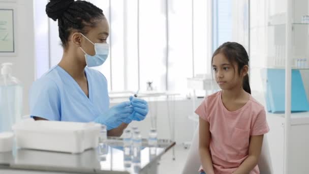 Pequeño niño observando cómo el médico con máscara protectora y guantes de seguridad llena la jeringa con la vacuna en el hospital mientras espera la vacunación. Concepto de atención sanitaria, prevención. — Vídeo de stock