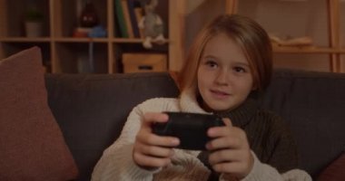 Joyce 'un elinde joystick tutan ve kullanan neşeli genç kızın yakın görüntüsü. Kanepede rahatça otururken sarı saçlı güzel bir çocuk oyun oynuyor. Boş zaman ve eğlence anlayışı.