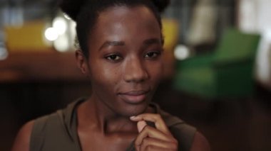 Binlerce yıllık Afro-Amerikan kadınının kameraya bakarken başını kaldırıp dönmesine yakından bakın. Çekici kadın pozu portresi. Bulanık arkaplan.