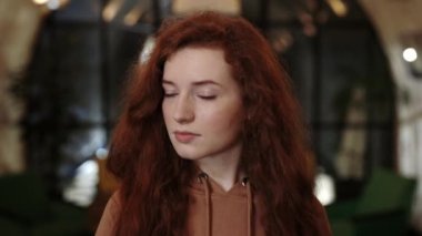 Bin yıllık kızıl saçlı bir kadının başını çevirip kameraya bakışının ekili görüntüsü. Mavi gözlü çekici bir kadının portresi. Bulanık arkaplan.